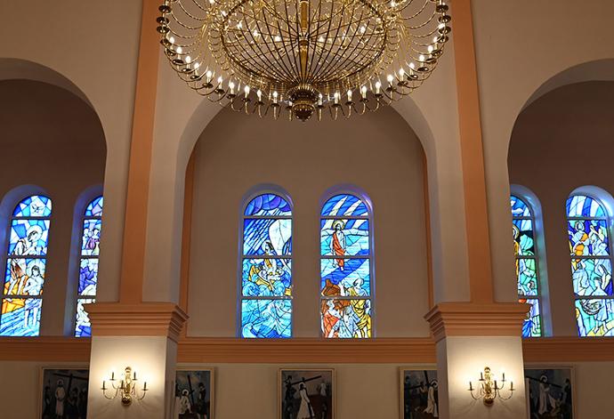 Unutrašnjost crkve s polukružnim lukovima, lusterom i vitrajima