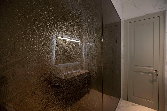 Interijer luksuznog toaleta s velikom staklenom reljefiranom površinom na zidu