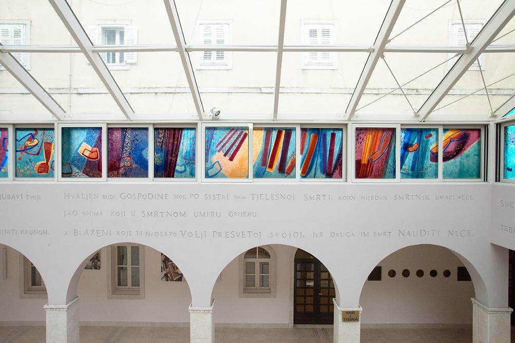 Bright space with a glass ceiling, painted windows, and semicircular arches.